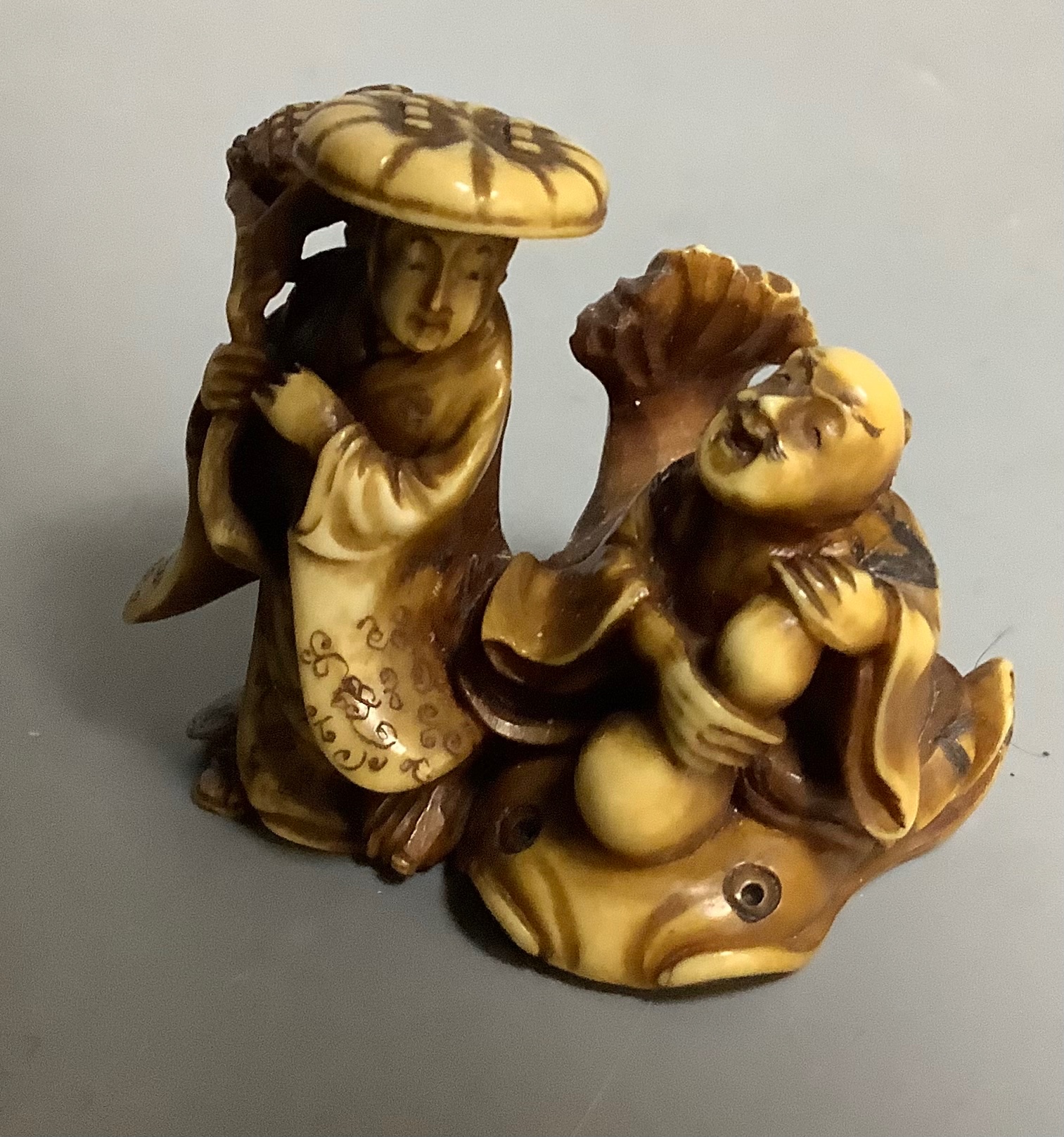 A Japanese stained ivory Netsuke of two figures, signed Masatsugo Kaigyokusai, Meiji period, 3cm high